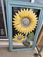 Full view of painted metal sunflower wall decor against house exterior