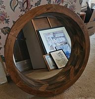 Front view of round mirror leaning on wall, shows natural wood frame and glass
