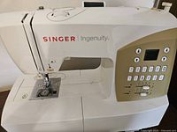 Front and top view of Singer 7436 Ingenuity sewing machine showing control panel and needle area