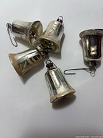 Five silver glass bell ornaments with hooks visible