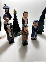 Group view of four carolers and two trees