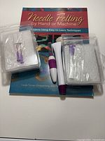 Front view of all items – book, two packaged needles, two felting tools
