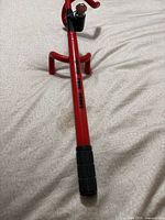 Full view of red steering wheel lock with black grip