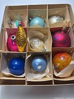 Box of nine assorted glass ornaments in individual compartments
