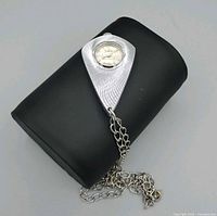 Front view of silver-tone Sheffield pendant watch resting on black support with chain visible