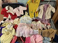 Overview of suitcase filled with multiple baby clothes pieces in assorted colours and fabrics