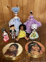 Group shot of six dolls and two plaques