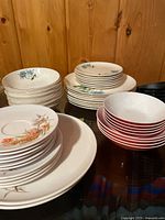 Stacks of blue floral china plates and bowls alongside red/white melamine bowls