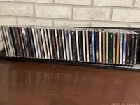 Row of approx. 40 CDs on rack showing assorted titles