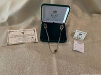 Necklace displayed in open case with certificate, info card and tag