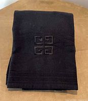 Folded black Givenchy bath towel showing embroidered 4G logo