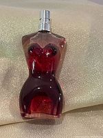 Front view of torso-shaped perfume bottle showing color and fill level