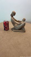 Full side view of mother and child figurine beside Coke can for scale