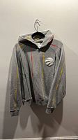 Front view of grey hoodie on hanger showing stripe graphics and overall condition