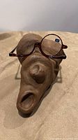 Full view of tortoise-shell makeup glasses resting on sculpture