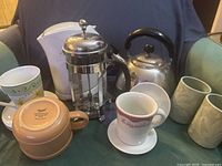 Group shot of French press, kettles, mugs, saucers