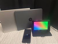 Front view of Lenovo laptop (closed), HP Stream laptop (closed), Verizon tablet in case powered on, Motorola smartphone charging