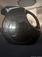 Profile view showing overall form, handle, ring motif, dark glaze