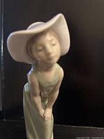 Front view of Lladro figurine showing girl's face, hat and dress