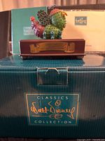 Figure on base atop branded box showing plaque