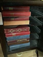 Stack of eight binder-style albums inside a gramophone cabinet