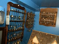 Wide view of three wooden racks filled with souvenir spoons mounted on blue wall