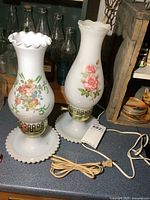 Both milk glass lamps showing overall form, floral decals, bases and cords