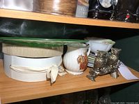 Shelf view showing uranium glass plate on box, owl shakers, footed bowl, pitcher