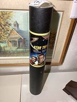 Full view of black tube containing the uncut Star Trek stamp sheet