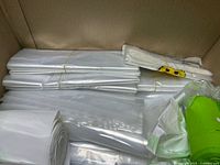 Stacks of white trash liners, clear bags roll, green bag roll in box