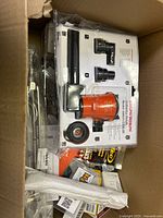 Open box showing assorted hardware supplies and orange bilge pump kit in packaging