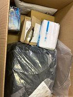 Top view of box showing black fabric item, white box, brown boxes, blue-patterned box