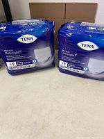 Two sealed Tena ProSkin Overnight underwear packs on table