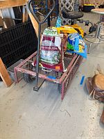 Garden wagon loaded with seed bags, showing handle and crate in background