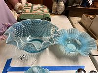 Large and small blue opalescent hobnail bowls on table