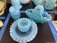 Group of blue opalescent Fenton glass items including vases, basket and paperweight