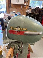 Left side of cowling showing Firestone decal, 10 HP marking, tiller handle and surface corrosion