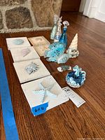 All items arranged: plaques in a row, glass bottles, fish, pumpkin, gnome and sea urchin visible