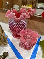 Both cranberry opalescent hobnail vases side by side