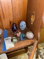 Group of six assorted art glass paperweights on shelf