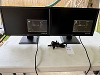 Front view showing both HP monitors powered on with OSD, cords visible