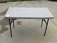 Overall view of 48" plastic folding table with folding legs