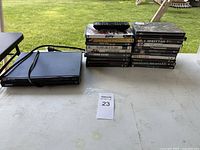 Stack of DVD cases, Sony DVD player with cords, remote on top