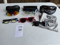 All seven eyewear pieces laid out with cases and pouch visible