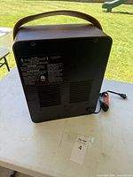 Rear view showing wood-grain finish, carry strap and safety label