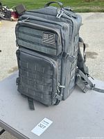 Front view showing MOLLE webbing, flag patch, compartments