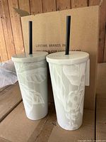 Two Starbucks Reserve tumblers with lids and straws in front of shipping box