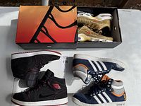 Overview showing all three sneaker pairs including Nike gold pair in box, Nike black high-tops, Adidas navy high-tops
