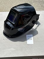 Overall view of black YesWelder auto-darkening helmet showing lens, side knobs, branding