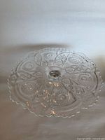 Top view of pressed-glass cake stand showing hobstar pattern and scalloped rim